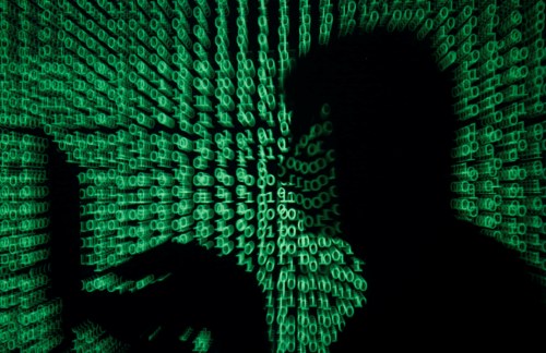 A man holds a laptop computer as cyber code is projected on him in this illustration picture taken on May 13, 2017. Capitalizing on spying tools believed to have been developed by the U.S. National Security Agency, hackers staged a cyber assault with a self-spreading malware that has infected tens of thousands of computers in nearly 100 countries. REUTERS/Kacper Pempel/Illustration - RTX35OS0
