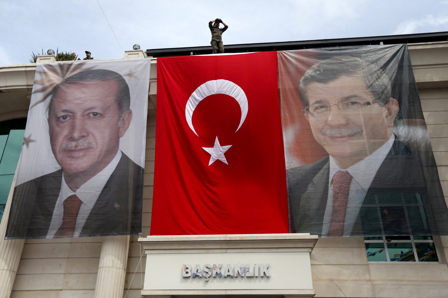 A special forces police officer takes security measures as he stands on top of a building where the portraits of Turkey's President Tayyip Erdogan (L), Prime Minister Ahmet Davutoglu and a Turkish flag are displayed in Istanbul, Turkey, June 3, 2015. REUTERS/Murad Sezer/File Photo - RTX2CSBG