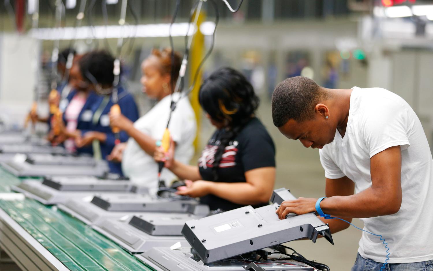 Workers on the assembly line replace the back covers of 32-inch television sets.