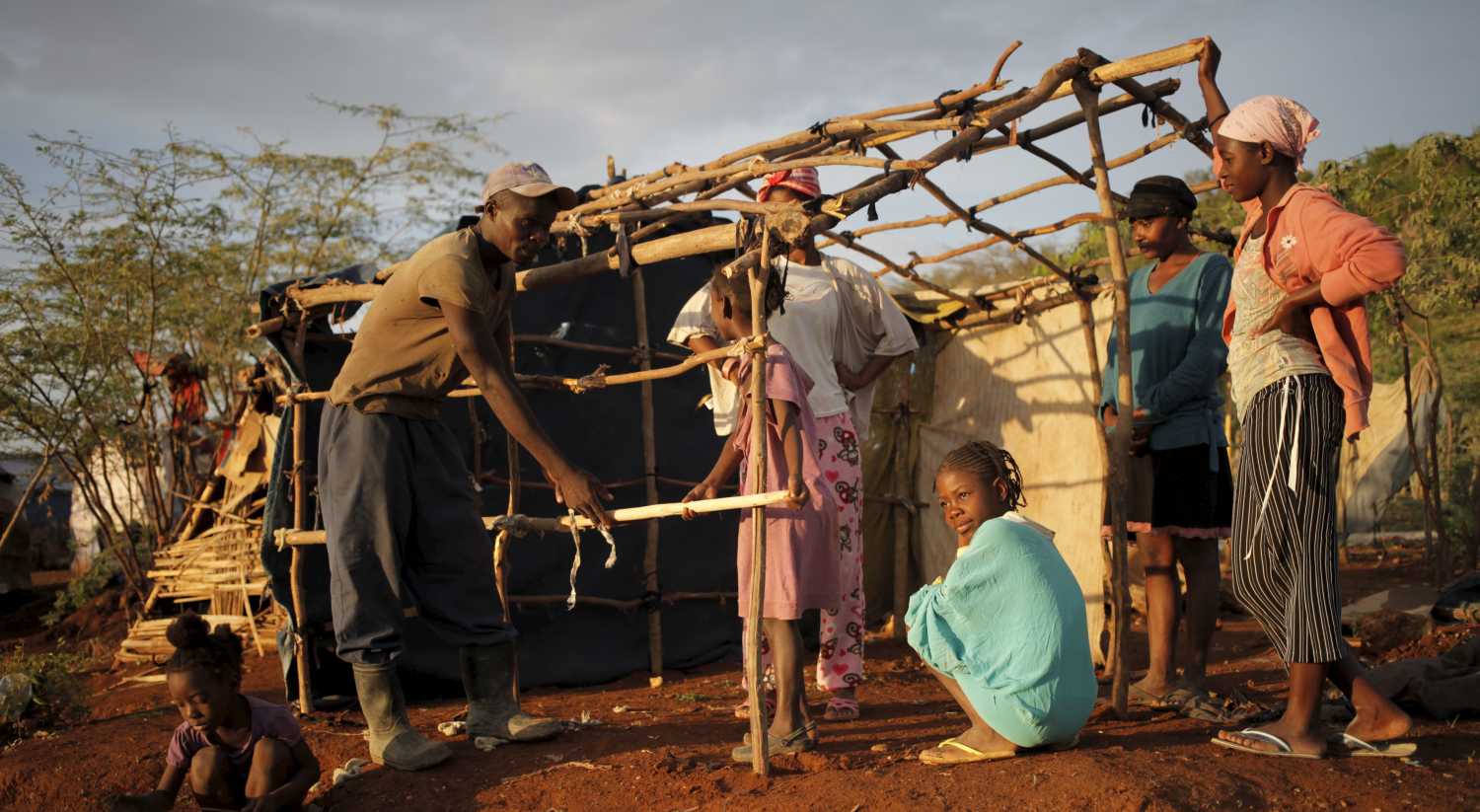 A man ties sticks to build a makeshift tent at a refugee camp for Haitians returning from the Dominican Republic on the outskirts of Anse-a-Pitres, Haiti, September 7, 2015. Dominican officials last month began implementing a controversial immigration program targeting Haitian migrants and Dominican-born people of Haitian descent. The program centers on round-ups and deportations that have triggered concerns about a slow-growing border migration crisis in the poorest country in the Americas. So far about 1,500 people have been deported at a pace of 50 to 100 per day, according to relief officials with access to records supplied by the Dominican government. The officials asked not to be identified because they were not authorized to discuss the number of deportees. Thousands more have fled the Dominican Republic out of fear of arrest or harassment, scared by neighbors, bosses, coworkers and police or immigration officials. Picture taken September 7, 2015. To match Feature HAITI-DOMINICAN/DEPORTEES REUTERS/Andres Martinez Casares - RTS1TZI
