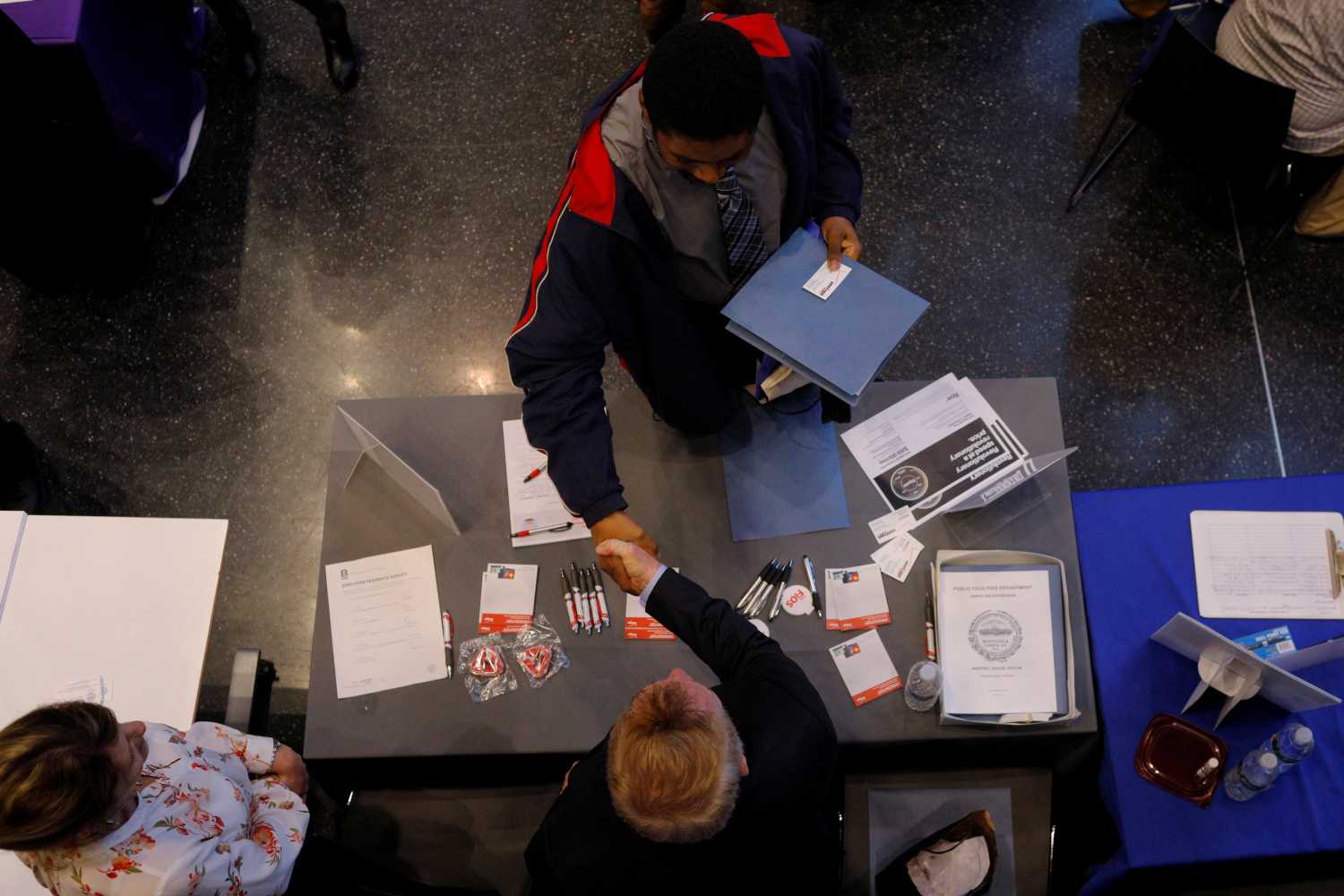 Job seeker Tony Harris shakes hands with a representative from Verizon at a City of Boston Neighborhood Career Fair in Boston