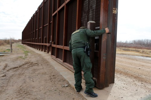 A U.S. Border patrol agent opens a gate on the fence along the Mexico border