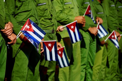 Army soldiers hold Cuban flags. Trump announced new regulations for Cuba on a speech Friday.