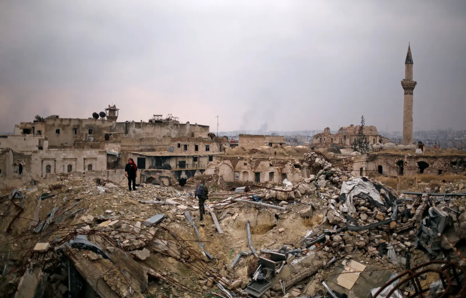 A member of forces loyal to Syria's President Bashar al-Assad stands with a civilian on the rubble of the Carlton Hotel, in the government controlled area of Aleppo, Syria December 17, 2016. REUTERS/Omar Sanadiki - RTX2VH44