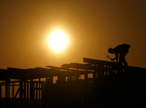 A construction worker hammers atop a construction project.