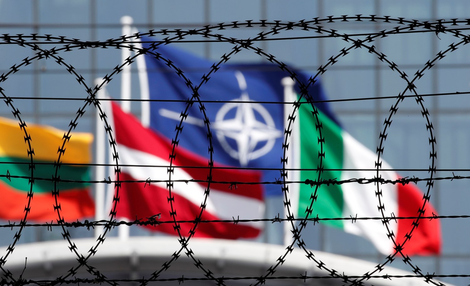 The NATO flag is seen through barbed wire as it flies in front of the new NATO Headquarters in Brussels, Belgium May 24, 2017. Member nations will inaugurate the new NATO headquarters during a summit in Brussels, Belgium May 25, 2017. REUTERS/Christian Hartmann - RTX37E51