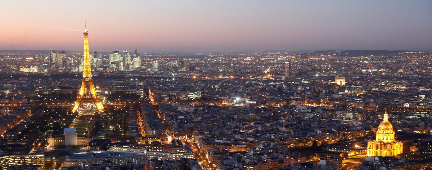 A general view shows the illuminated Eiffel Tower (L), the Hotel des Invalides (R) and rooftops