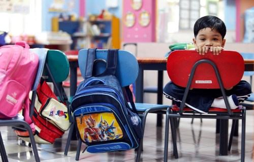 A preschooler stays in class as he refuses to join his classmates for outdoor activities during his first day of school in Putrajaya