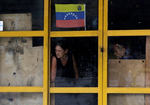 A couple look through a window during a strike called to protest against Venezuelan President Nicolas Maduro's government in Caracas, Venezuela,