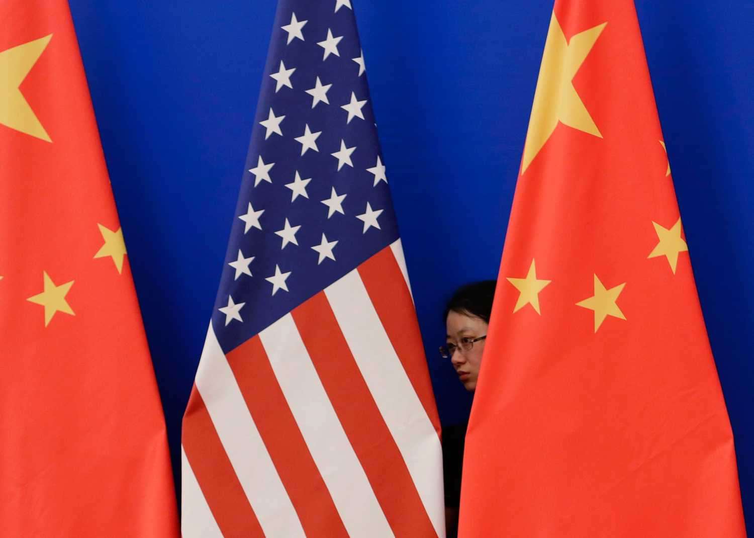 A member of staff from Chinese government adjusts U.S. and Chinese national flags before a news conference for the 6th round of U.S.-China Strategic and Economic Dialogue at the Great Hall of the People in Beijing, July 10, 2014. REUTERS/Jason Lee (CHINA - Tags: POLITICS BUSINESS) - RTR3XZ0B