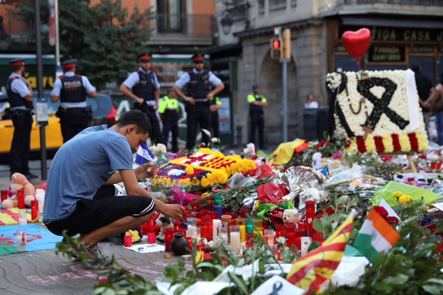 A man lights a candle at an impromptu memorial where a van crashed into pedestrians at Las Ramblas in Barcelona, Spain August 21, 2017. REUTERS/Susana Vera - RTS1CLTL