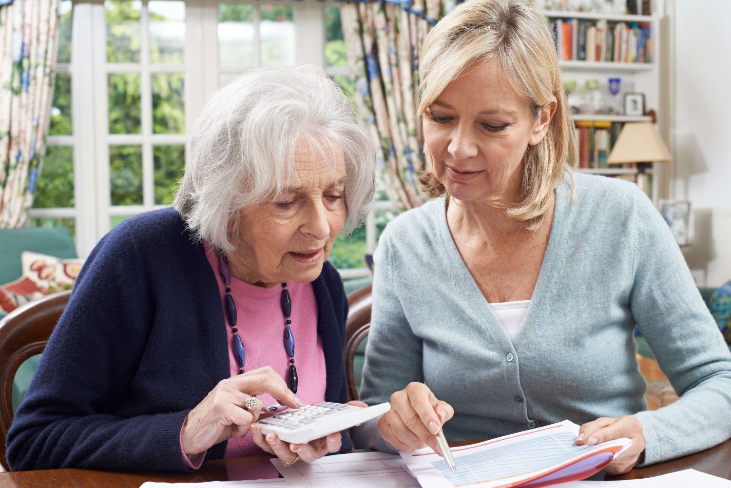 Mature Woman Helping Senior Neighbor With Home Finances