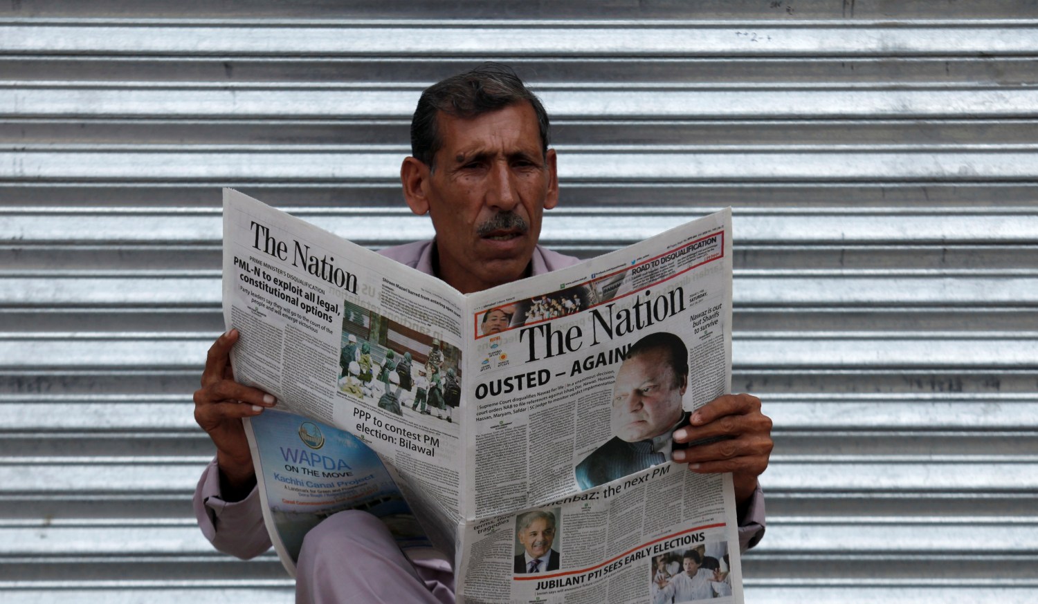 DATE IMPORTED:July 29, 2017A man reads a newspaper with news about the disqualification of Pakistan's Prime Minister Nawaz Sharif by the Supreme Court, in Peshawar, Pakistan July 29, 2017. REUTERS/Fayaz Aziz