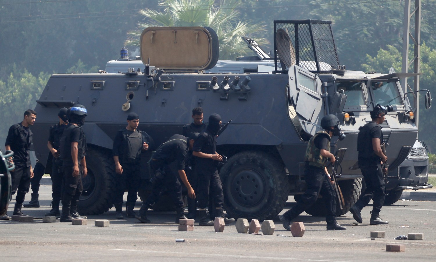 Riot police gather behind an armoured vehicle during clashes with members of the Muslim Brotherhood and supporters of deposed Egyptian President Mohamed Mursi, at Rabaa Adawiya square, where they are camping, in Cairo August 14, 2013. Egyptian security forces killed at least 30 people on Wednesday when they cleared a camp of Cairo protesters who were demanding the reinstatement of deposed President Mohamed Mursi, his Muslim Brotherhood movement said. REUTERS/Amr Abdallah Dalsh (EGYPT - Tags: POLITICS CIVIL UNREST) - RTX12KYJ