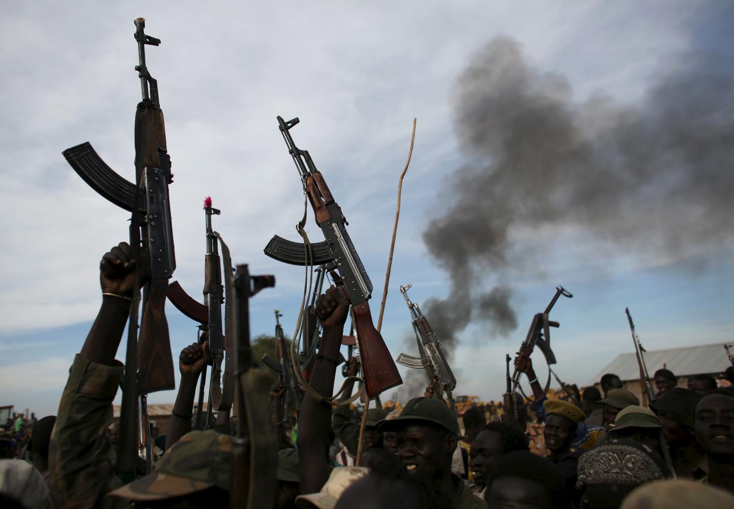 Rebel fighters hold up their rifles as they walk in front of a bushfire in a rebel-controlled territory in Upper Nile State, South Sudan February 13, 2014. South Sudan's rebels said on Tuesday that government soldiers had launched attacks against their positions in oil-rich Unity State in what they said was a violation of a peace deal signed in August. Picture taken February 13, 2014. REUTERS/Goran Tomasevic TPX IMAGES OF THE DAY - RTS7JEQ