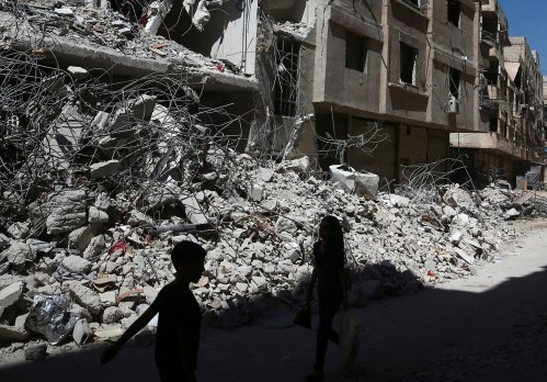 Children walk past rubble of damaged buildings at Ain Tarma, eastern Damascus suburb of Ghouta, Syria July 19, 2017. REUTERS/Bassam Khabieh - RTX3C32C