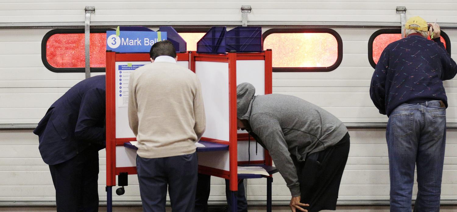 Voters look over their ballots at a fire station while a crew leaves on an emergency call during the U.S. presidential election in Arlington, Virginia, U.S., November 8, 2016. REUTERS/Joshua Roberts - HT1ECB900D0DE