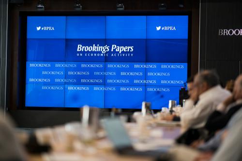 People sitting at a table in front of a screen that says "Brookings Papers"