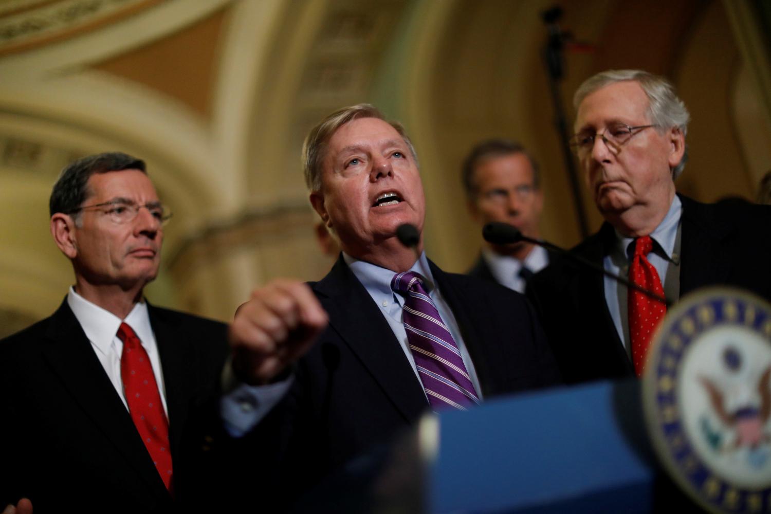 Sen. Lindsey Graham (R-SC), accompanied by Sen. John Barrasso (R-WY), and Senate Majority Leader Mitch McConnell, speaks with reporters following the party luncheons on Capitol Hill in Washington, U.S., September 19, 2017. REUTERS/Aaron P. Bernstein - RC1D74AF44C0