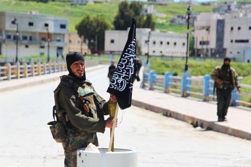 A Nusra Front fighter carries a shell near a Nusra Front flag on his weapon in Jisr al-Shughour town, after rebels took control of the area April 25, 2015. Islamist insurgents including al-Qaeda's wing in Syria Nusra Front seized the strategic northwestern Syrian town of Jisr al-Shughour on Saturday, for the first time in the four year conflict. Syrian state media said the army had redeployed to the town's surroundings "to avoid civilian casualties". Opposition fighters and the Syrian Observatory for Human rights said that the town was now totally controlled by the insurgents. REUTERS/Ammar Abdullah - GF10000072359