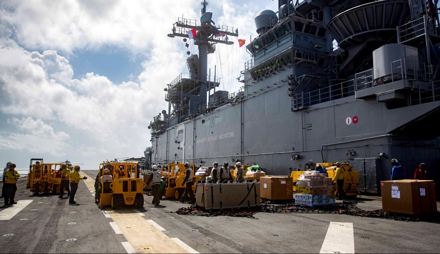 Sailors aboard the amphibious assault ship USS Kearsarge (LHD 3) move pallets of supplies on the flight deck during a replenishment-at-sea with the fast combat support ship USNS Supply (T-AOE 6) for relief efforts in the aftermath of Hurricane Maria in Puerto Rico on September 28, 2017. Picture taken on September 28, 2017. Courtesy Ryre Arciaga/U.S. Navy/Handout via REUTERS ATTENTION EDITORS - THIS IMAGE HAS BEEN SUPPLIED BY A THIRD PARTY. - RC1F885AD890