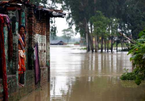 A woman looks out from her house at a flood affected area in Nepal