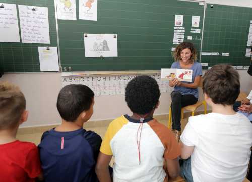 Children listen to their teacher on the first day of the new school year in a primary school in Nice
