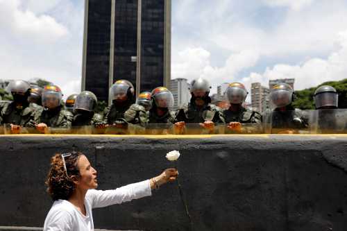 A demonstrator holds up a flower in front of riot policemen during a women's march to protest against President Nicolas Maduro's government in Caracas, Venezuela, May 6, 2017. REUTERS/Carlos Garcia Rawlins - RC1EB3B6BBB0
