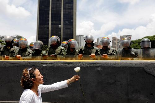 A demonstrator holds up a flower in front of riot policemen during a women's march to protest against President Nicolas Maduro's government in Caracas, Venezuela, May 6, 2017. REUTERS/Carlos Garcia Rawlins - RC1EB3B6BBB0