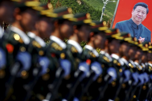 A picture of Chinese President Xi Jinping is seen behind soldiers of China's People's Liberation Army marching during a training session for a military parade to mark the 70th anniversary of the end of the World War Two, at a military base in Beijing, China, August 22, 2015.
