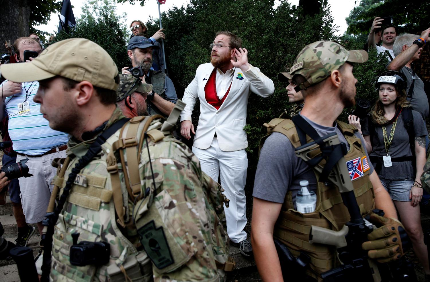 A white nationalist stands behind militia members after he scuffled with a counter demonstrator in Charlottesville, Virginia, U.S., August 12, 2017. REUTERS/Joshua Roberts - RC164F32C360