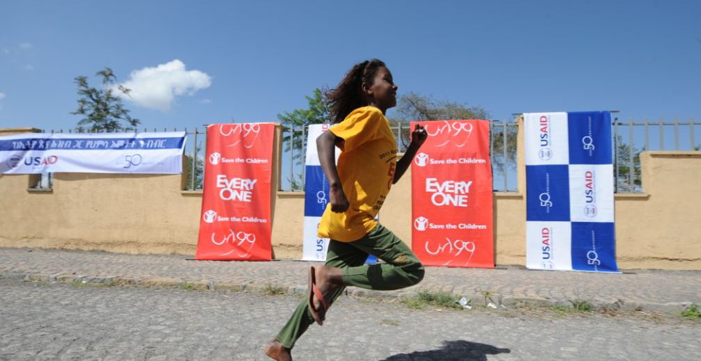 Child running with USAID icon in the background,