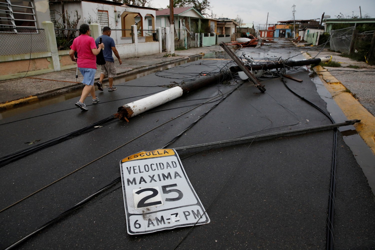 Photo: People walk next to fallen electric poles and traffic sings after the area was hit by Hurricane Maria in Salinas, Puerto Rico, September 21, 2017. REUTERS/Carlos Garcia Rawlins