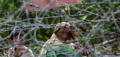 A Rohingya refugee woman and boy looks on through barbed wire as they wait for boat to cross the border through Naf river in Maungdaw, Myanmar, September 7, 2017.REUTERS/Mohammad Ponir Hossain