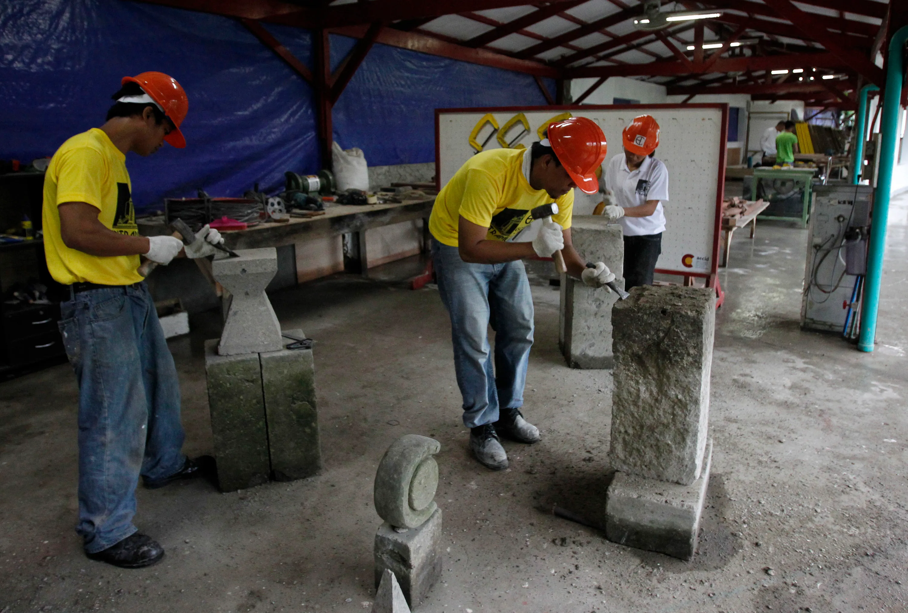 Students of the Escuela Taller technical school, which is funded by the Spanish government, carve adobe stones while waiting for the arrival of Spain's Queen Sofia (not pictured) in Intramuros, Manila July 3, 2012. Queen Sofia is on a five-day visit to the Philippines to inspect development projects which receive funding assistance from the Spanish government. REUTERS/Erik De Castro (PHILIPPINES - Tags: SOCIETY EDUCATION) - GM1E87312SK01
