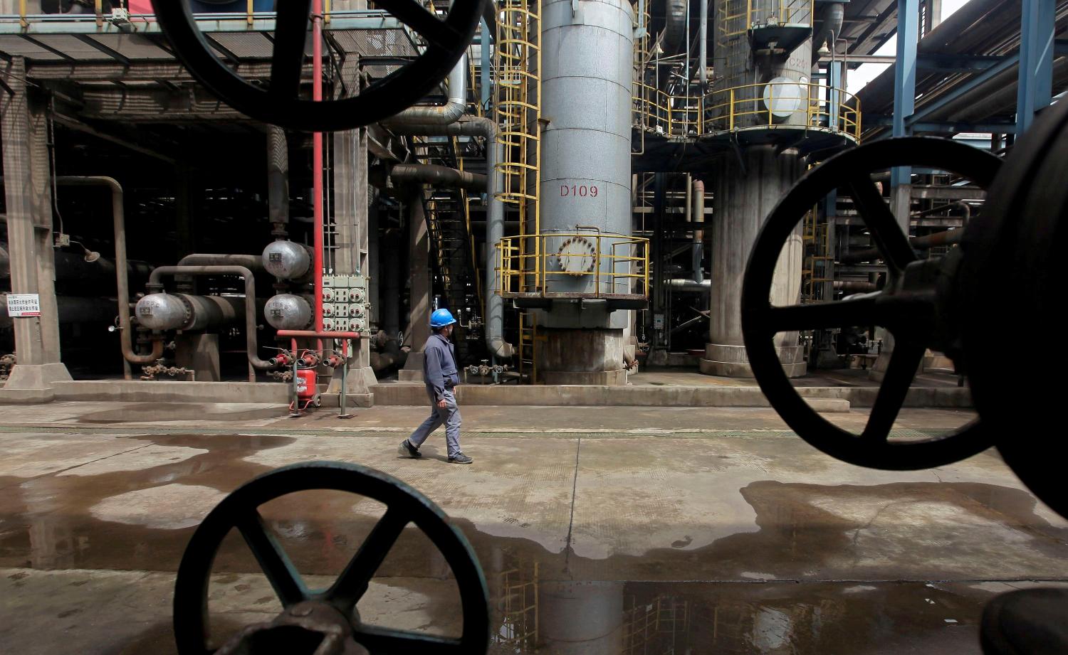 A worker walks past oil pipes at a refinery in Wuhan, Hubei province March 23, 2012. REUTERS/Stringer/File Photo - S1BETTQQDPAA