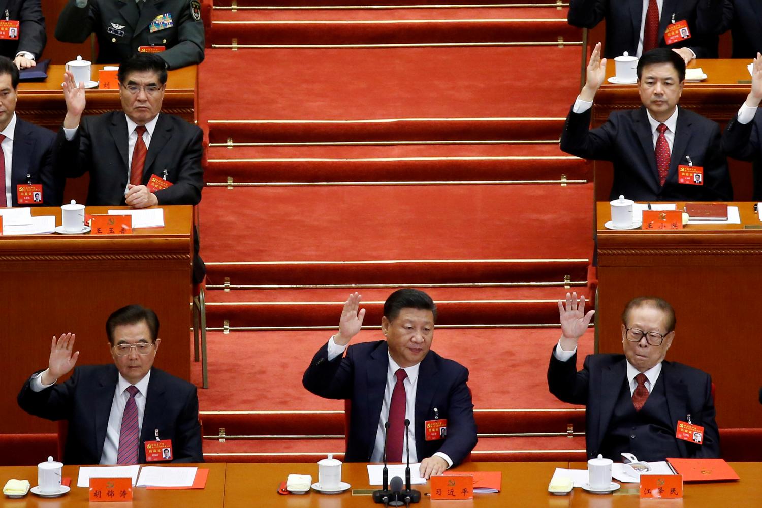 (L to R) Former Chinese president Hu Jintao, Chinese President Xi Jinping and former Chinese president Jiang Zemin raise their hands as they take a vote at the closing session of the 19th National Congress of the Communist Party of China, in Beijing, China October 24, 2017. REUTERS/Thomas Peter TPX IMAGES OF THE DAY - RC186FB9D730