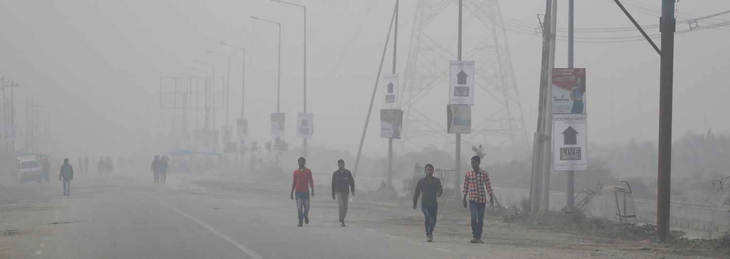 People walk through smog near Delhi, India November 13, 2017. REUTERS/Cathal McNaughton - RC1601BC1140