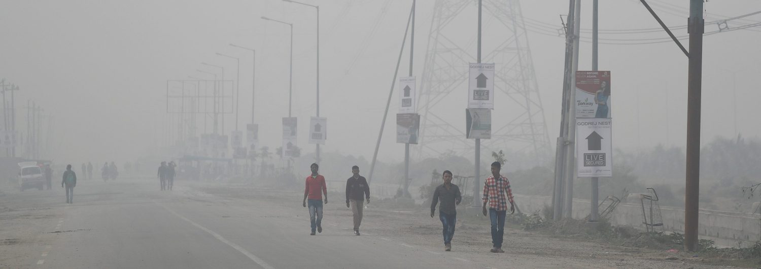 People walk through smog near Delhi, India November 13, 2017. REUTERS/Cathal McNaughton - RC1601BC1140
