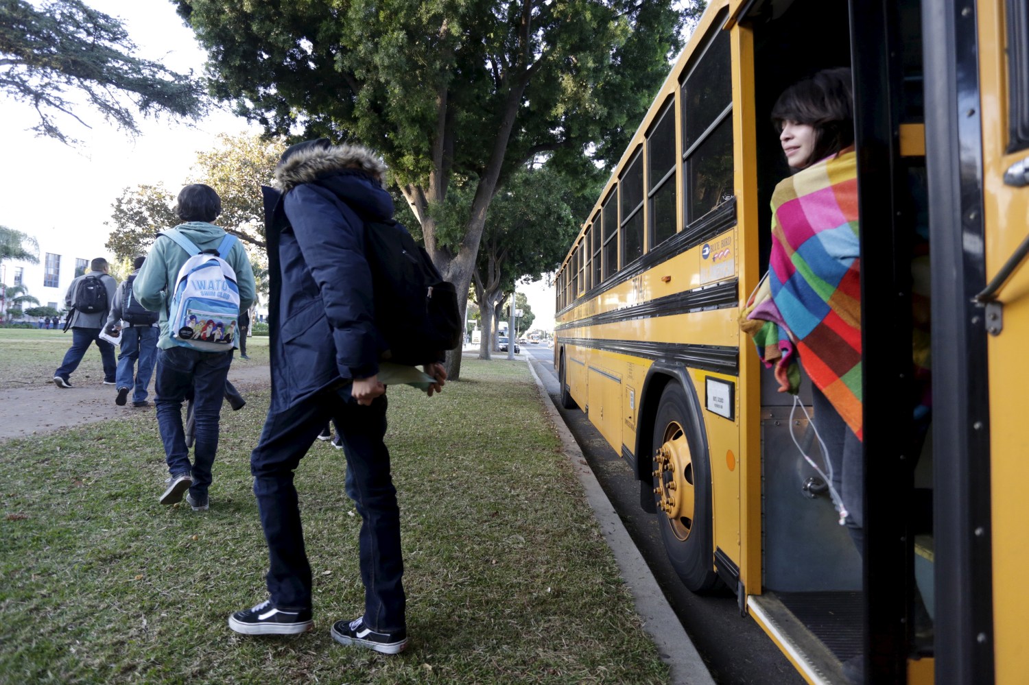 Students exit a bus as they arrive at Venice High School in Los Angeles, California