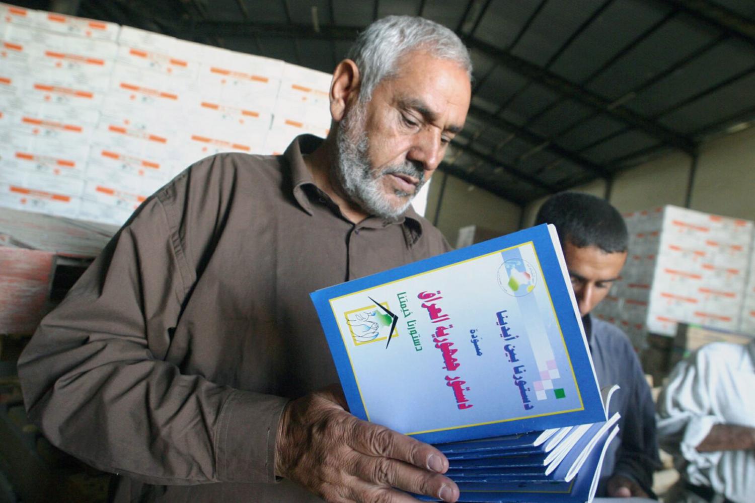 A man reads a booklet about the Iraqi draft constitution in the holy city of Najaf October 9, 2005. [Iraq will impose special security measures including travel restrictions and a gun ban for several days on either side of an October 15] referendum on the new constitution, the government said on Saturday. - PBEAHUNWKED