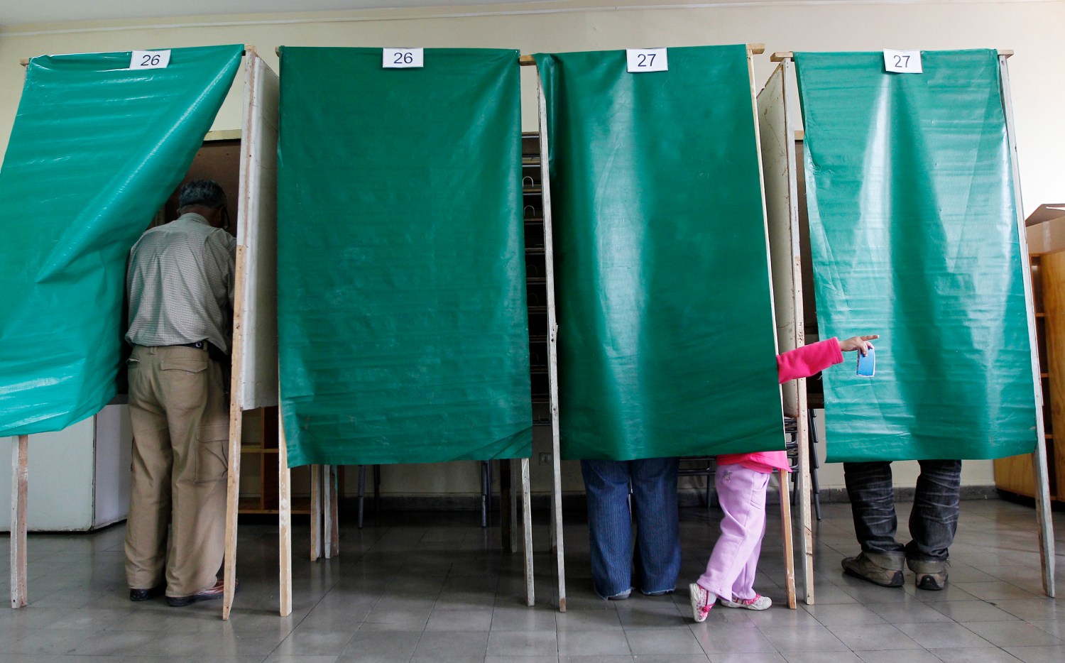 A child gestures as people cast their vote at a public school during municipal elections in Valparaiso city, about 121 km (75 miles) northwest of Santiago, October 28, 2012. Chilean voters will elect mayors and councilmen across 15 political regions on Sunday. REUTERS/Eliseo Fernandez (CHILE - Tags: POLITICS ELECTIONS) - GM1E8AT03GE01
