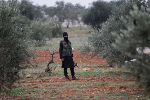 A member of al Qaeda's Nusra Front carries his weapon as he stands in an olive tree field, near villages which the Nusra Front said they have seized control of from Syrian rebel factions, in the southern countryside of Idlib, December 2, 2014. Picture taken December 2, 2014.