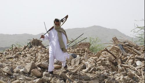 A man walks on the ruins of a house in Afghanistan.