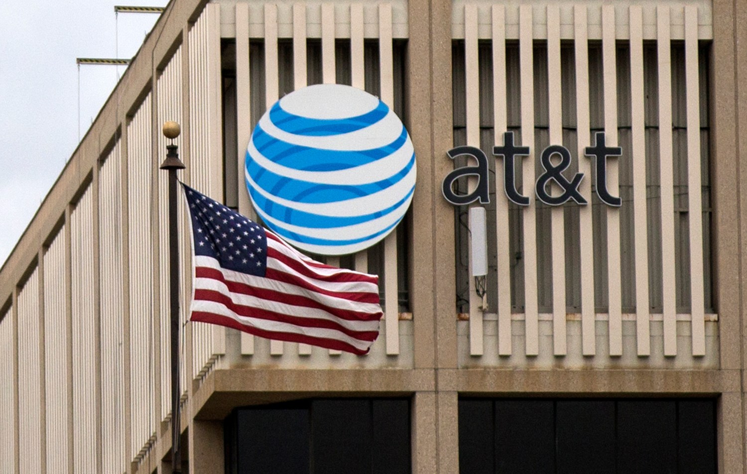 An AT&T Logo is pictured as a U.S. flag flutters in the foreground in Pasadena
