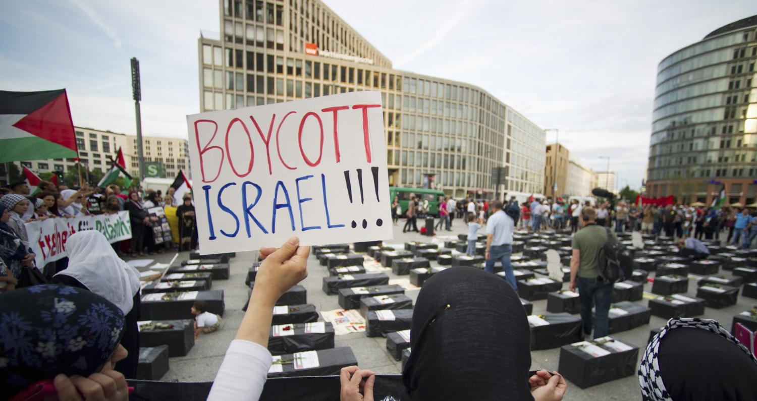 A woman holds a sign which reads "Boycott Israel" while attending a demonstration. REUTERS/Steffi Loos (GERMANY - Tags: POLITICS CIVIL UNREST) - GM1EA8206QF02