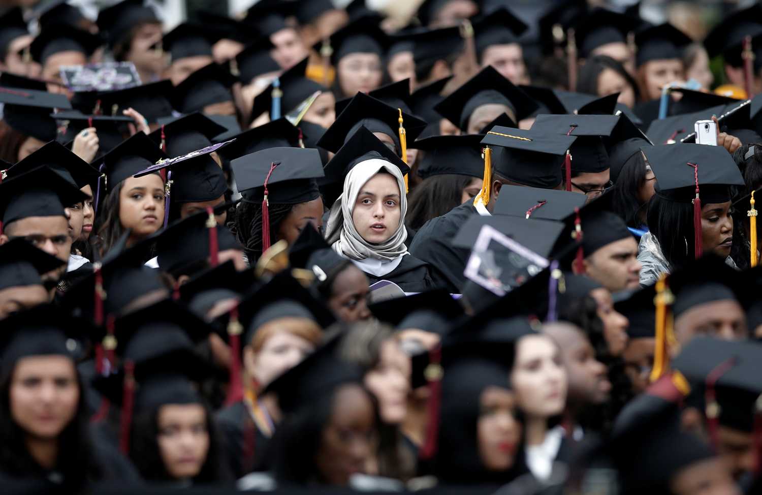 Graduating students of the City College of New York sit together in their caps and gowns during the College's commencement ceremony in the Harlem.