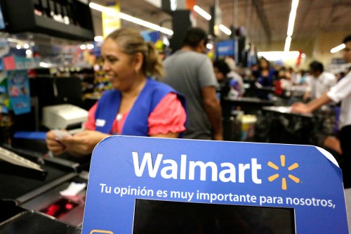 A cashier smiles beyond a Walmart logo.