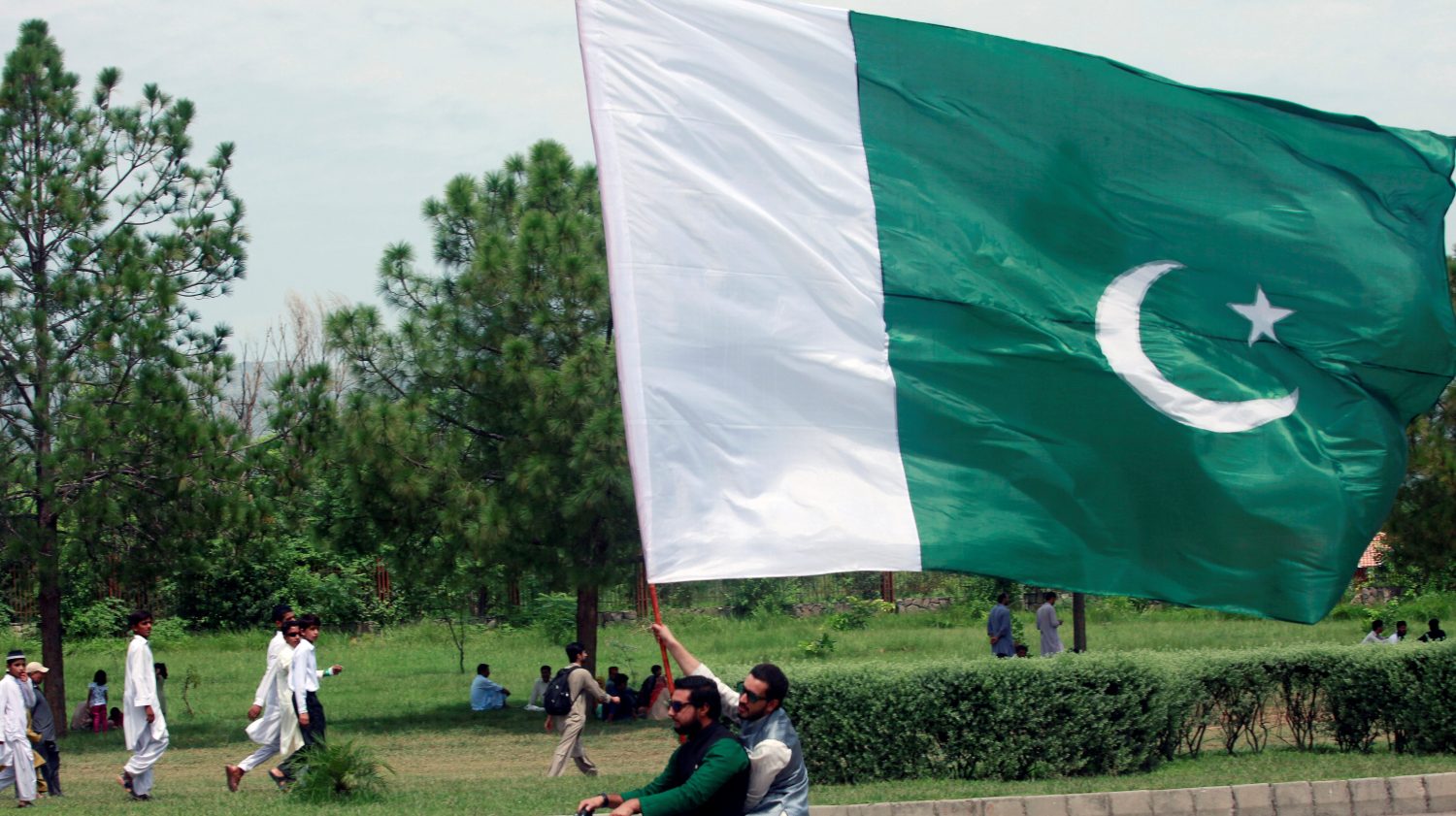 A man on the motor bike holds a national flag as he watches an air show to celebrate the 70th Independence Day in Islamabad, Pakistan August 14, 2017. REUTERS/Faisal Mahmood - RC1E2B34B240