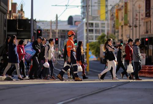 Pedestrians cross a road near a construction site.